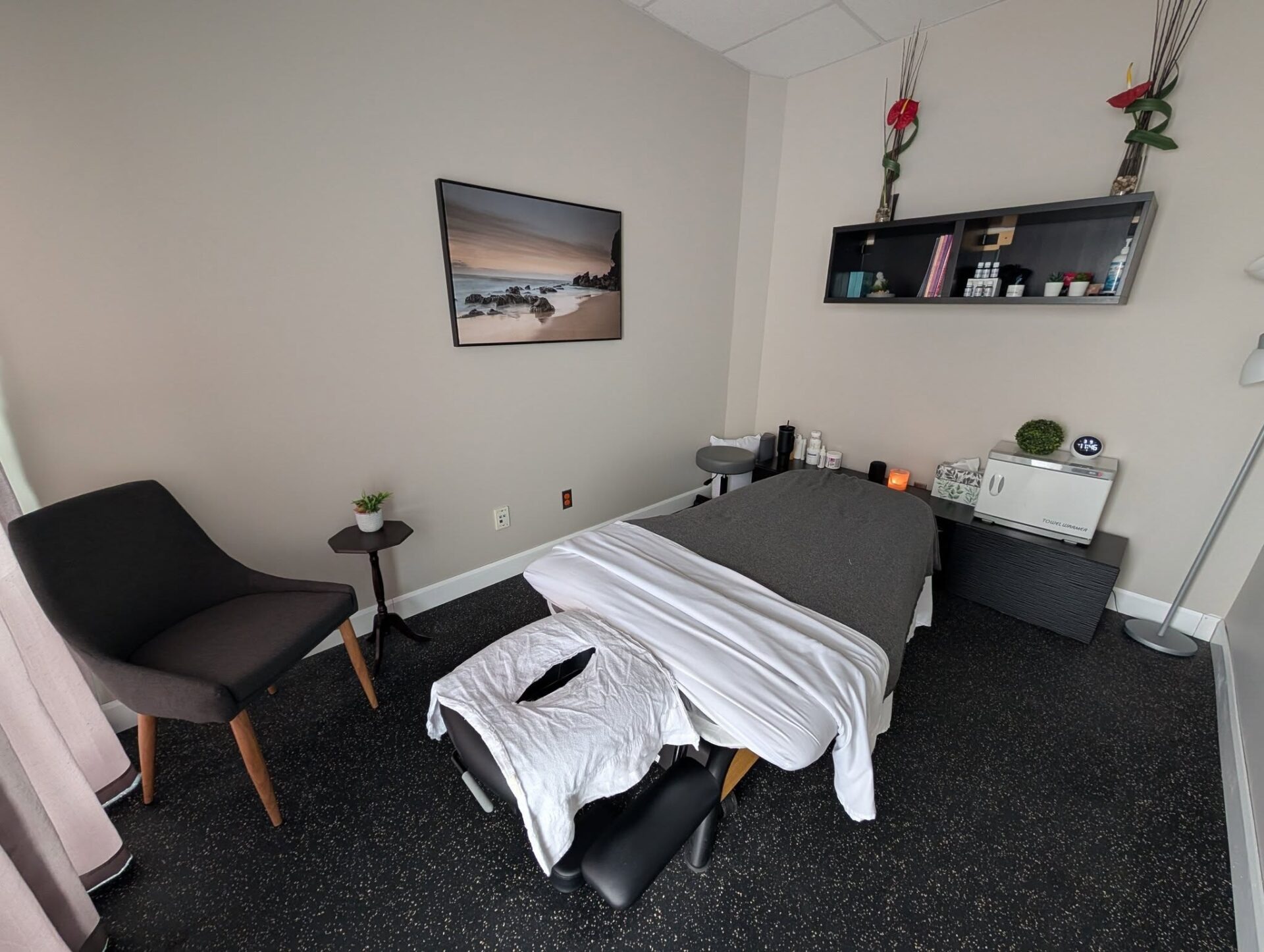 La salle de soin : table de massage drapée de blanc, fauteuil et lumière douce